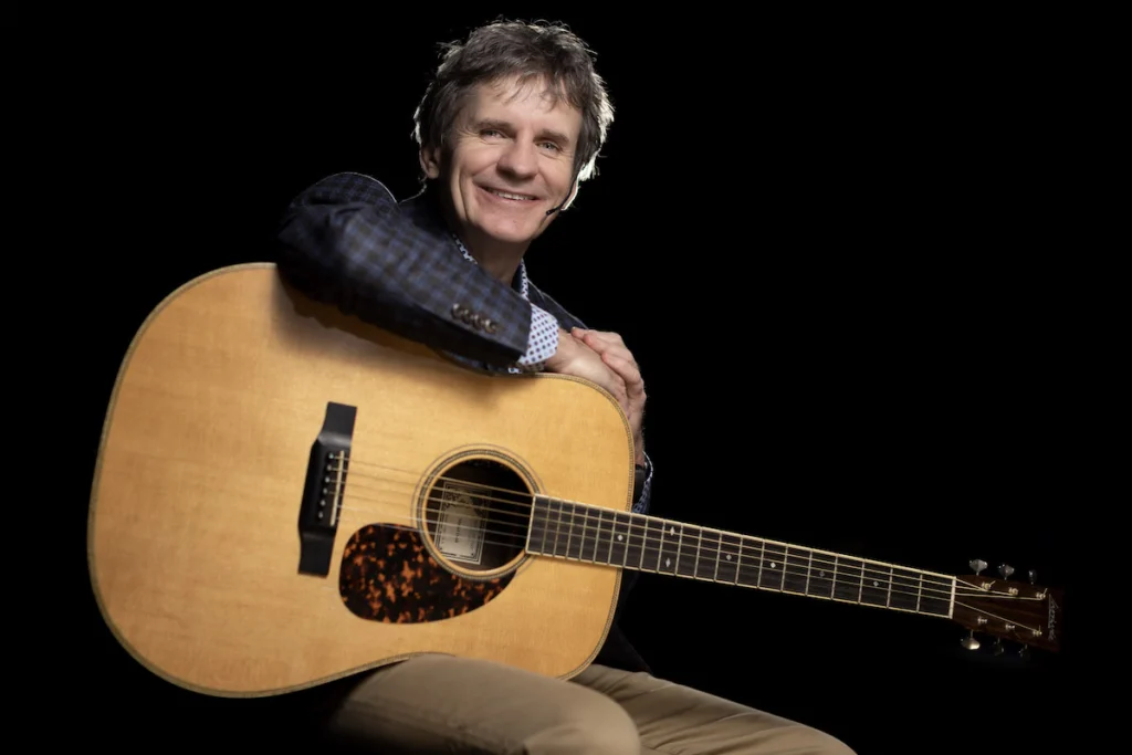 Kevin Ryan on stage with arm over acoustic guitar